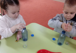 Dzieci wrzucają koraliki do butelek po wodzie mineralnej